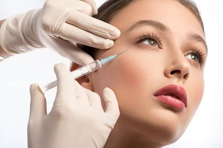 سرنگ تزريق مزوژل روي صورت يک خانم جوان قرار گرفته است در پس زمينه سفيد.